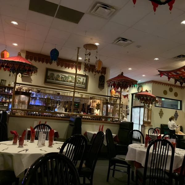 The interior of INDIA'S Restaurant, featuring tables with red napkins, a bar, and Indian-themed decor.