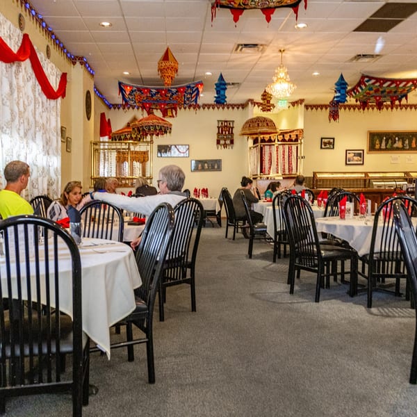 Diners seated at tables in INDIA'S Restaurant, featuring ornate Indian decor and a buffet line.